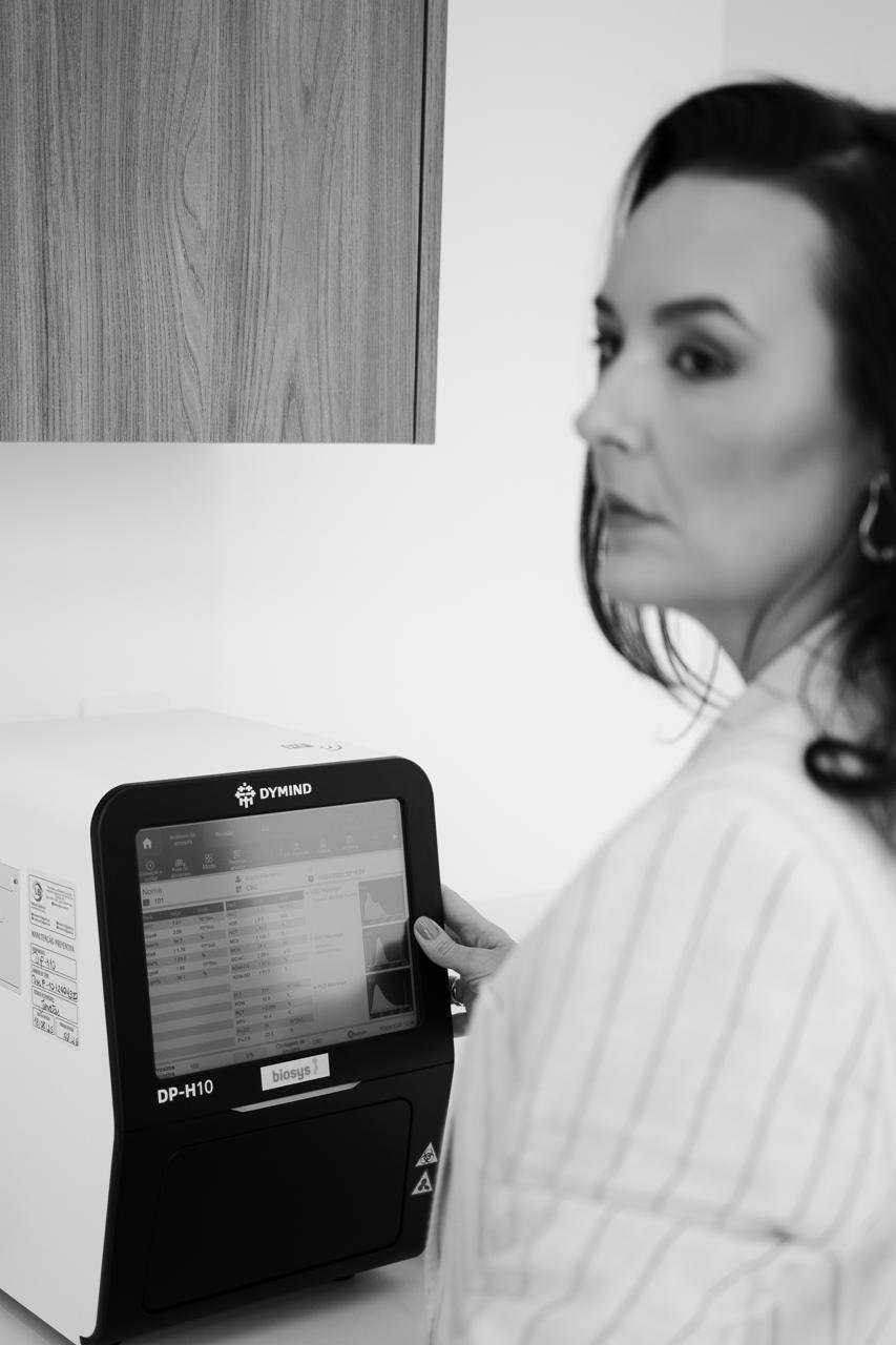 Dra. Andrezza Medina ao lado do analisador hematológico do consultório