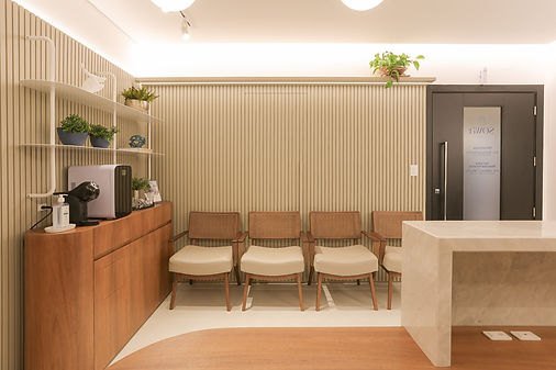 Sala de espera da clínica, com poltronas e painel ripado